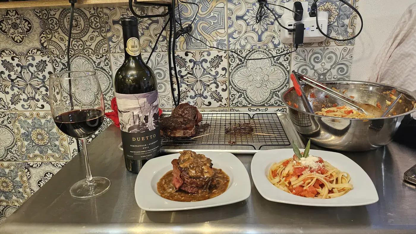 Mesa servida de noche con vino tinto, corte y pasta