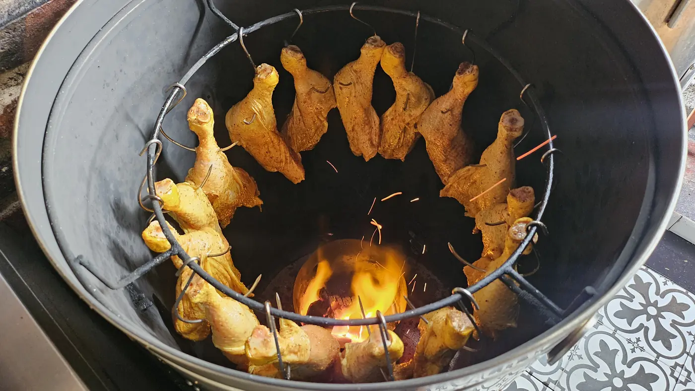 Piernas de pollo doradas alrededor del fuego en el asador vertical