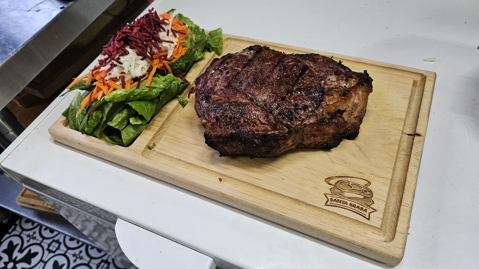 Ribeye a punto sobre tabla de madera con el logo de Santa Brasa grabado
