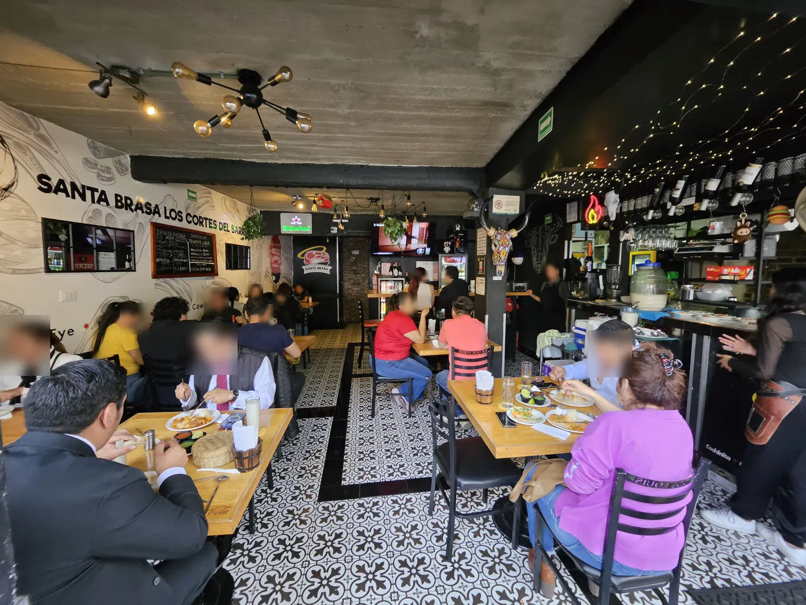 El salón de día con el mural Santa Brasa Los Cortes del Barrio y el piso de mosaico