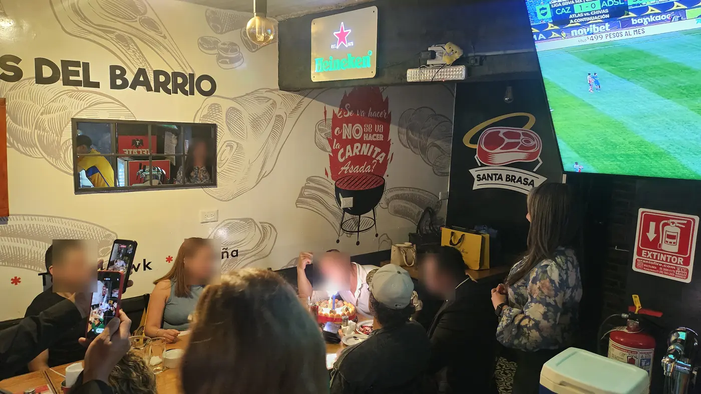 Clientes viendo el partido bajo el mural de la casa